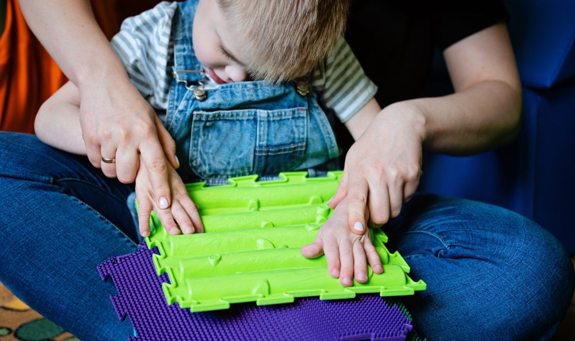 Sensory Play for Kids with Special Needs. Help and Activities for kids with disabilities, Cerebral Palsy. Boy with Cerebral Palsy playing with Sensory Mat Massage Game Puzzle Mats for Kids