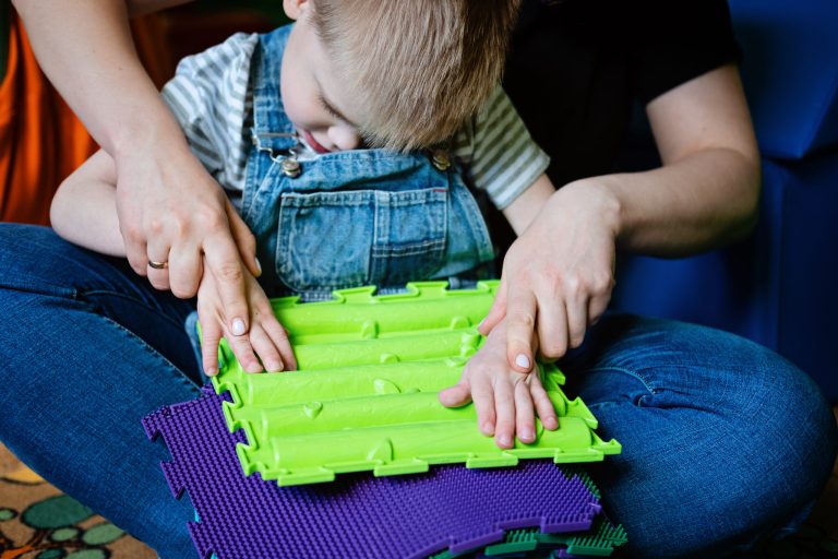 Sensory Play for Kids with Special Needs. Help and Activities for kids with disabilities, Cerebral Palsy. Boy with Cerebral Palsy playing with Sensory Mat Massage Game Puzzle Mats for Kids